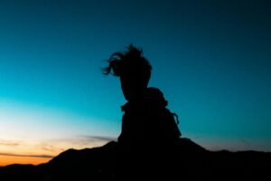 Shadow of a person with short hair standing in front of a sunset