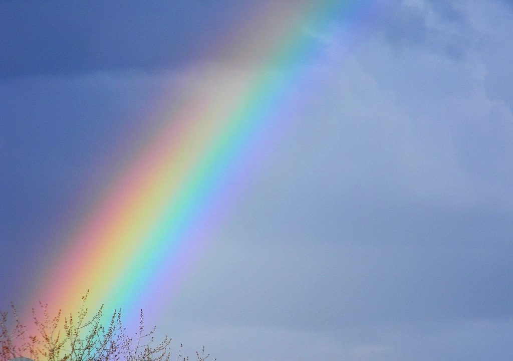 Hopeful rainbow in front of blue sky